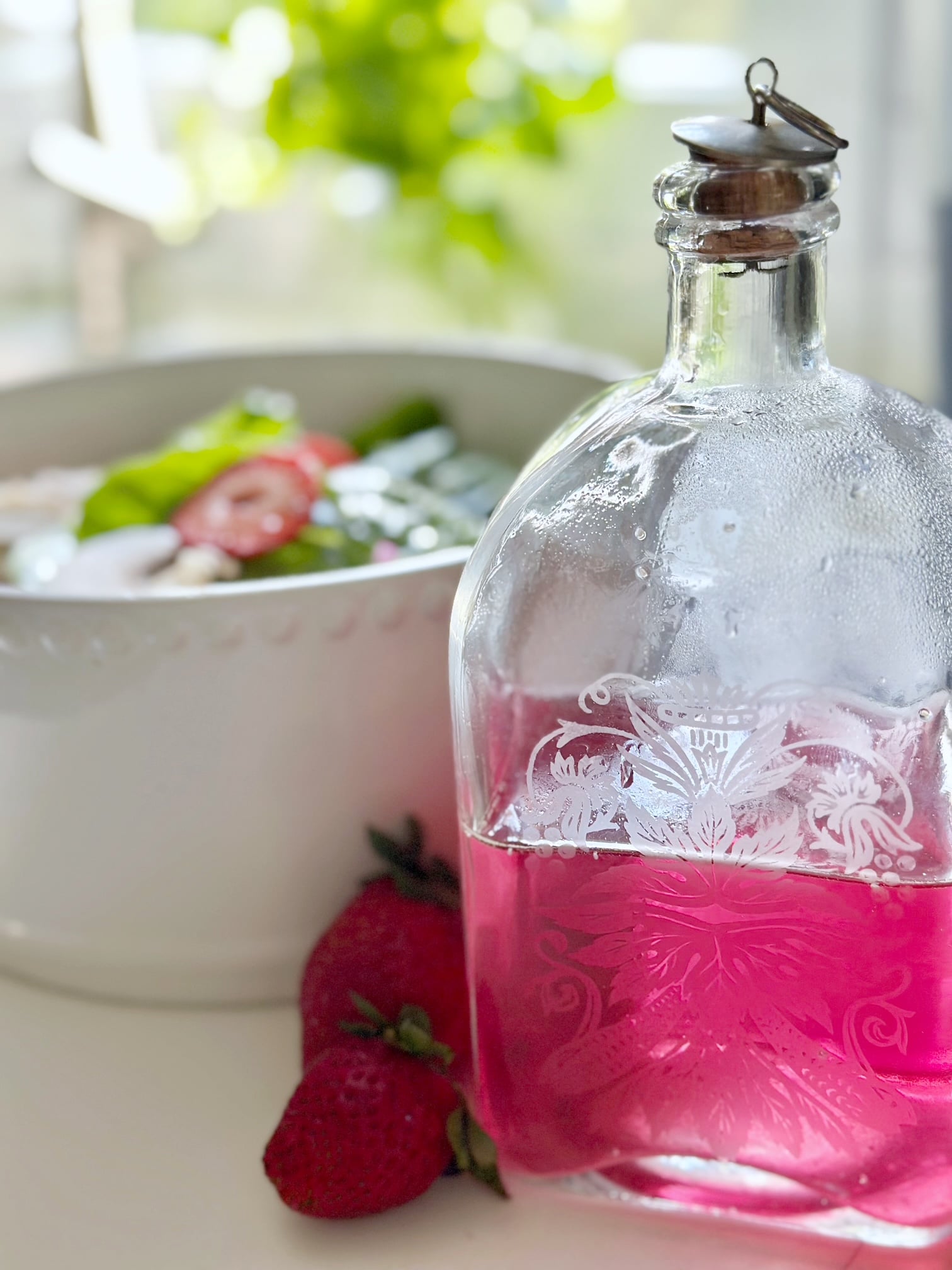 Chive blossom vinegar in front of a salad.