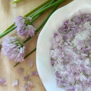Chive flower salt with chive stems nearby.