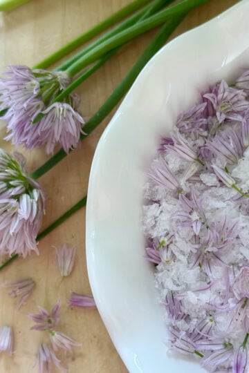 Chive flower salt with chive stems nearby.