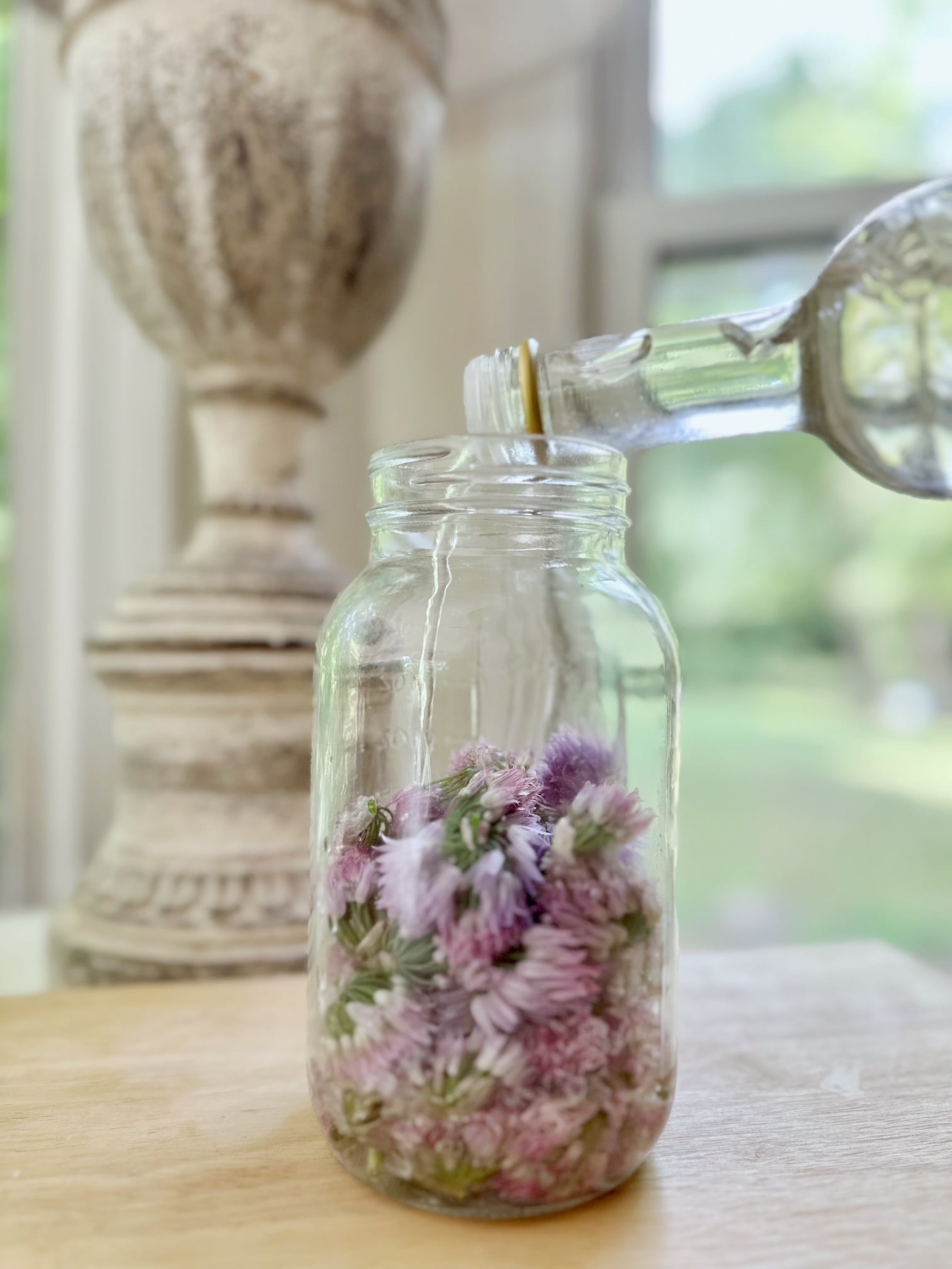 Pouring vinegar over blossoms in a jar.