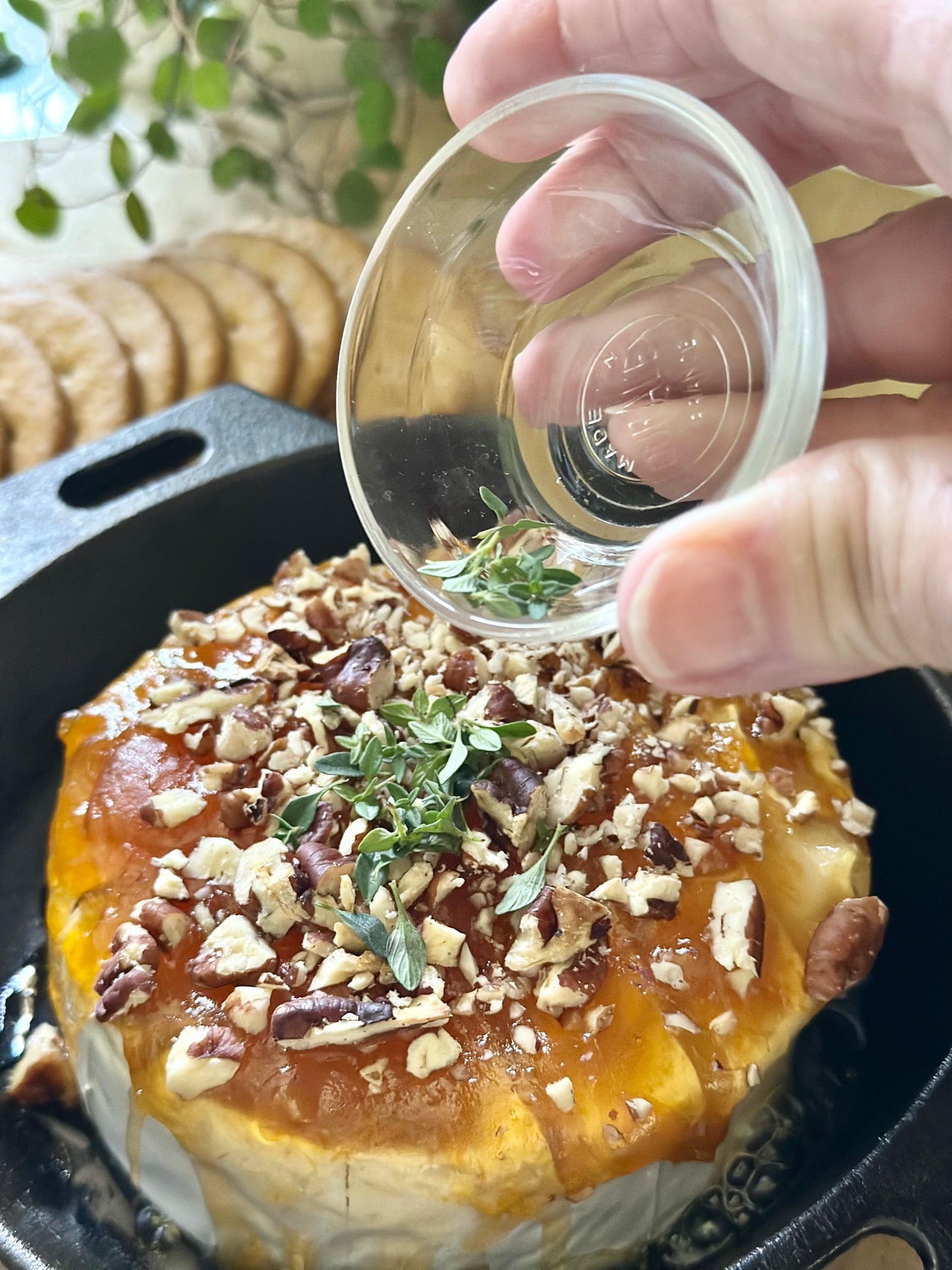 Adding chopped thyme to the baked brie with preserves and nuts. 