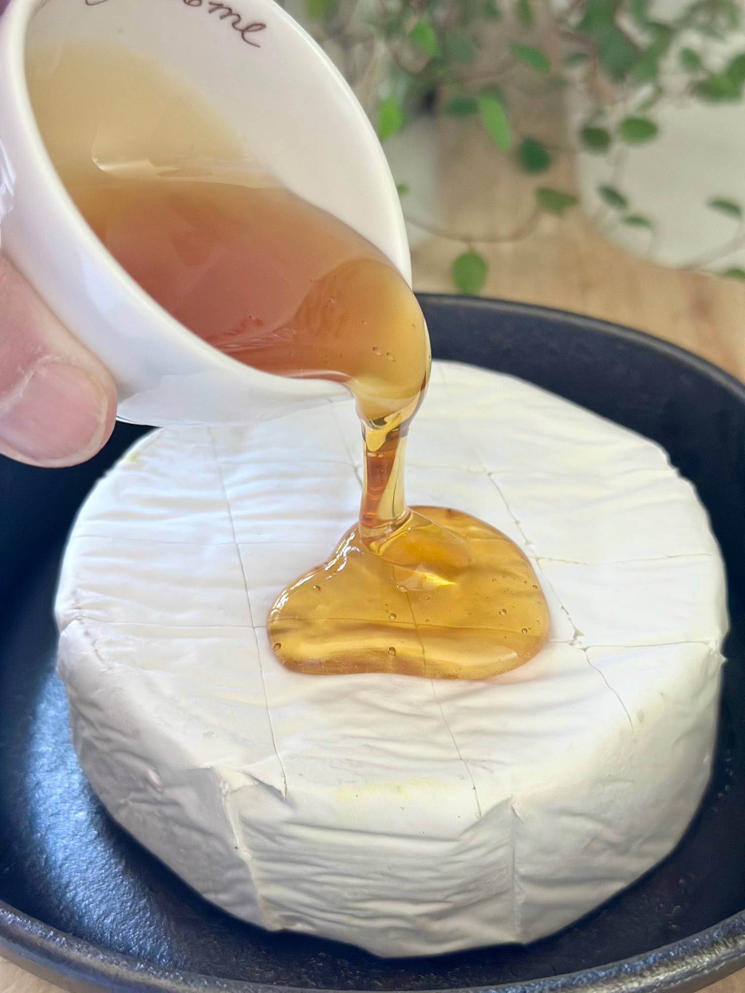 Drizzling the top of the brie with honey. 