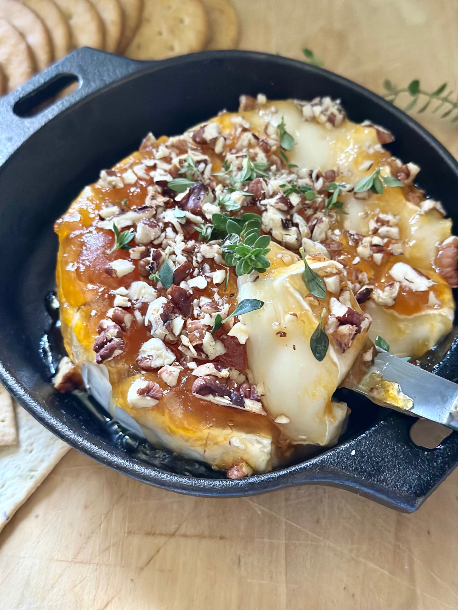 A knife slicing baked brie. 