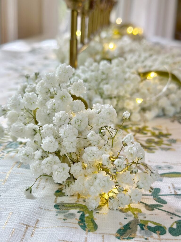 A close up of fresh baby's breath garland with twinkle lights and ribbon. 