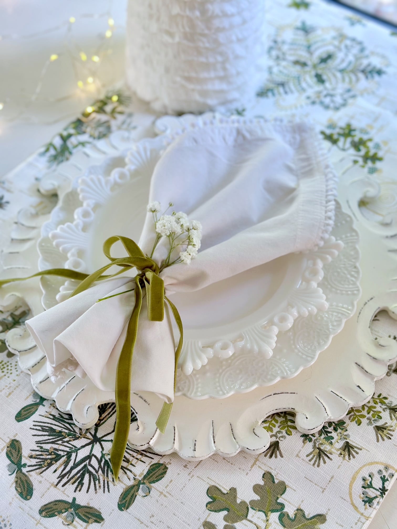 A sprig of baby's breath tucked behind a velvet ribbon around a cloth napkin. 