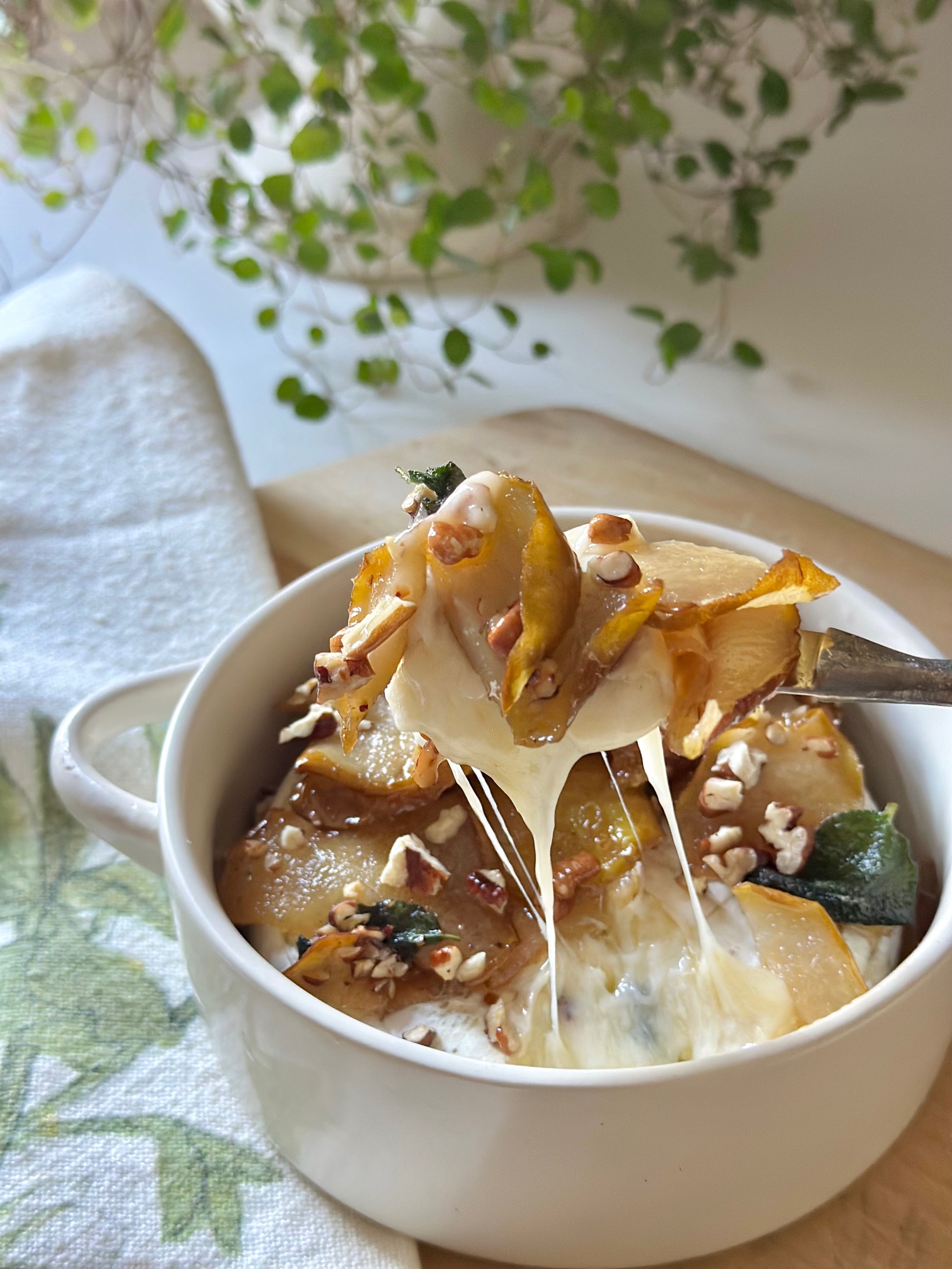 A knife scooping up baked brie with pears.