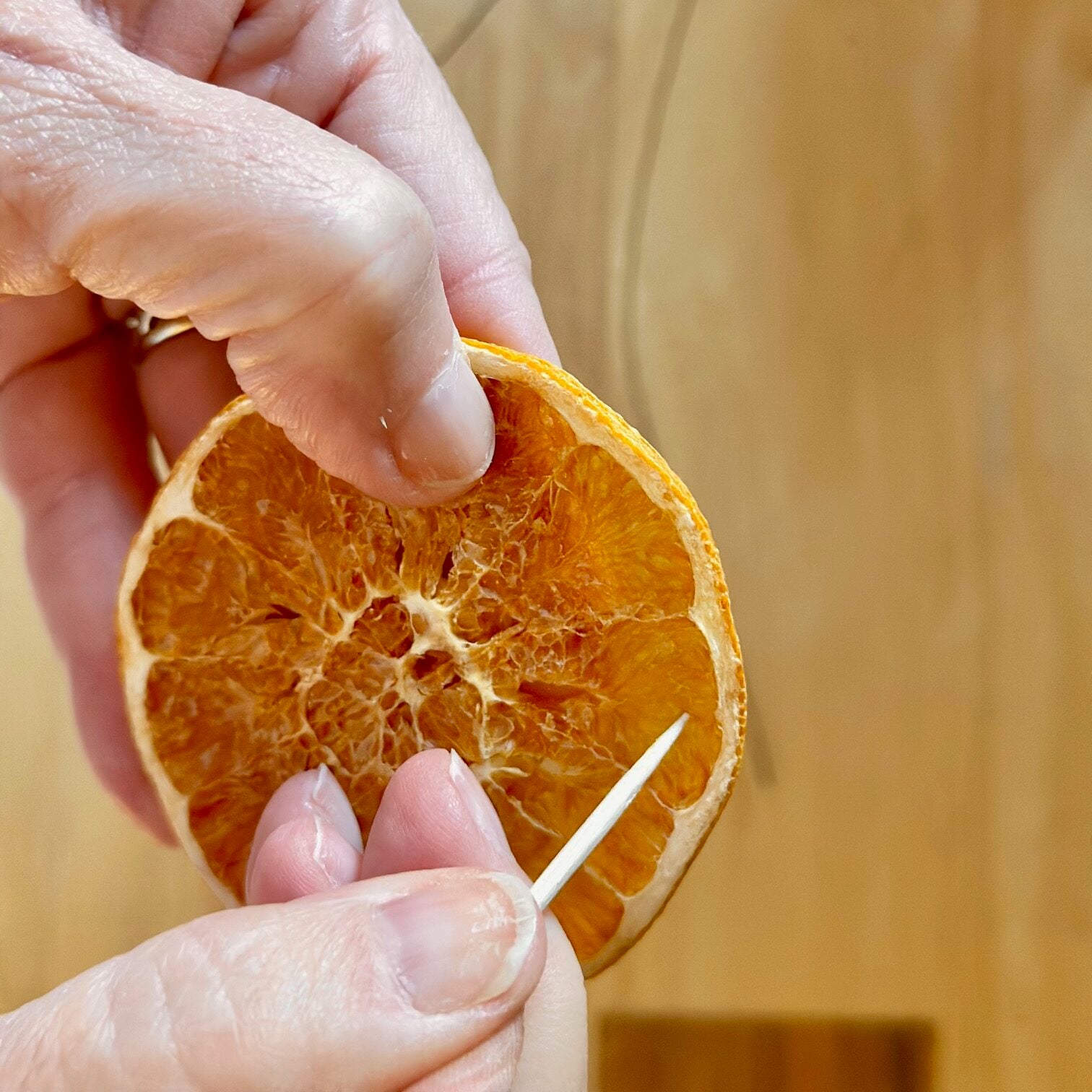 Piercing a toothpick through a dried orange slice. 