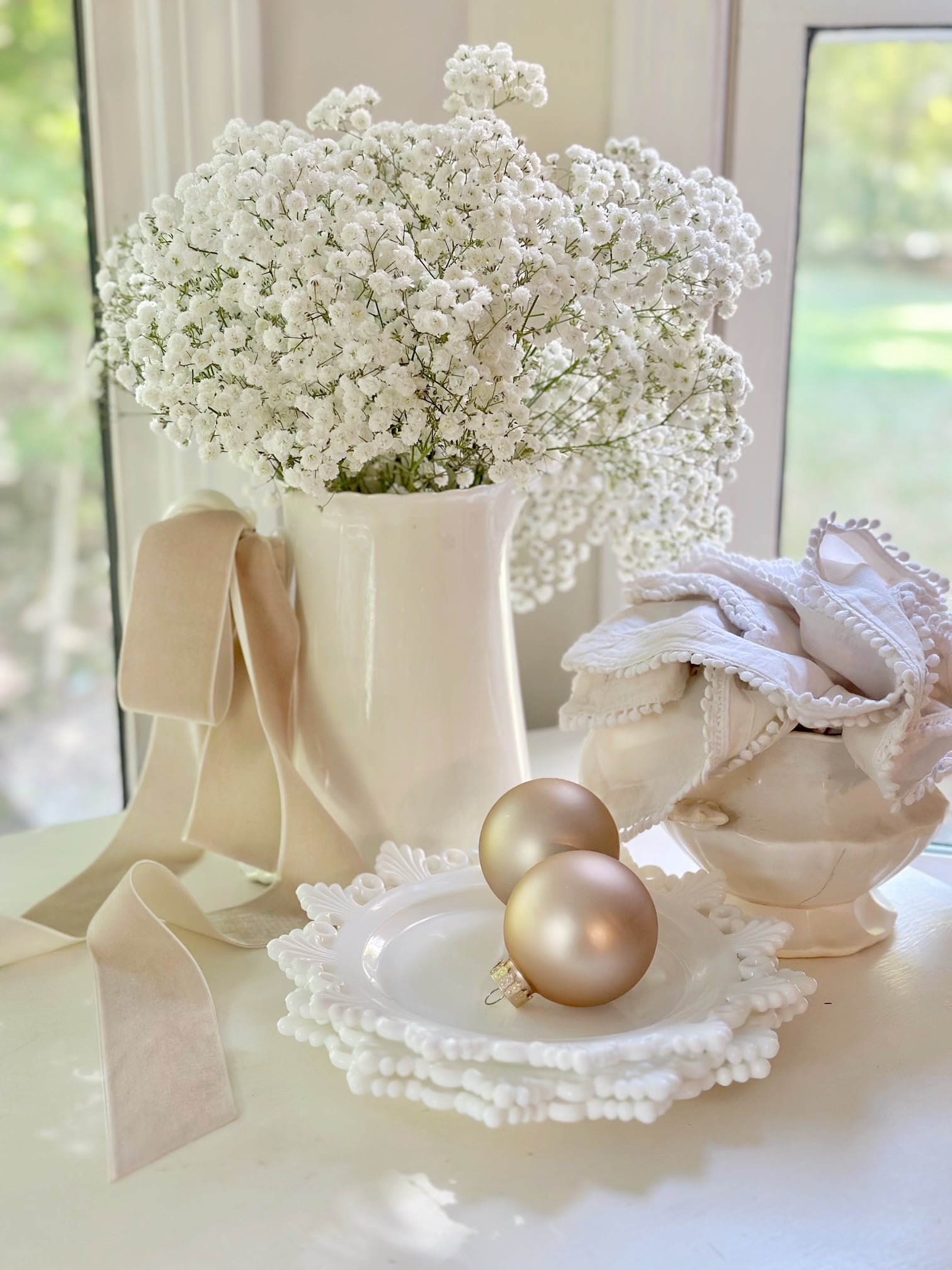 A white vintage pitcher filled with fresh baby's breath. 